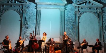 Capella de Ministrers en concert. Els cantants Èlia Casanova i Pi de Vittorio en primer pla; d'esquerra a dreta, Carles Magraner, Robert Cases, Lixsania Fernández, Pau Ballester, David Antich, Eduard Navarro i Aziz Samsaoui. Autora: Lluna Issa Casterà.